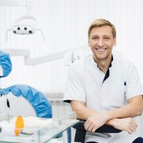 Portrait of smiling caucasian man dentist posing at modern dental office.