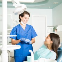 Smiling Dentist In Uniform Talking To Girl At Clinic