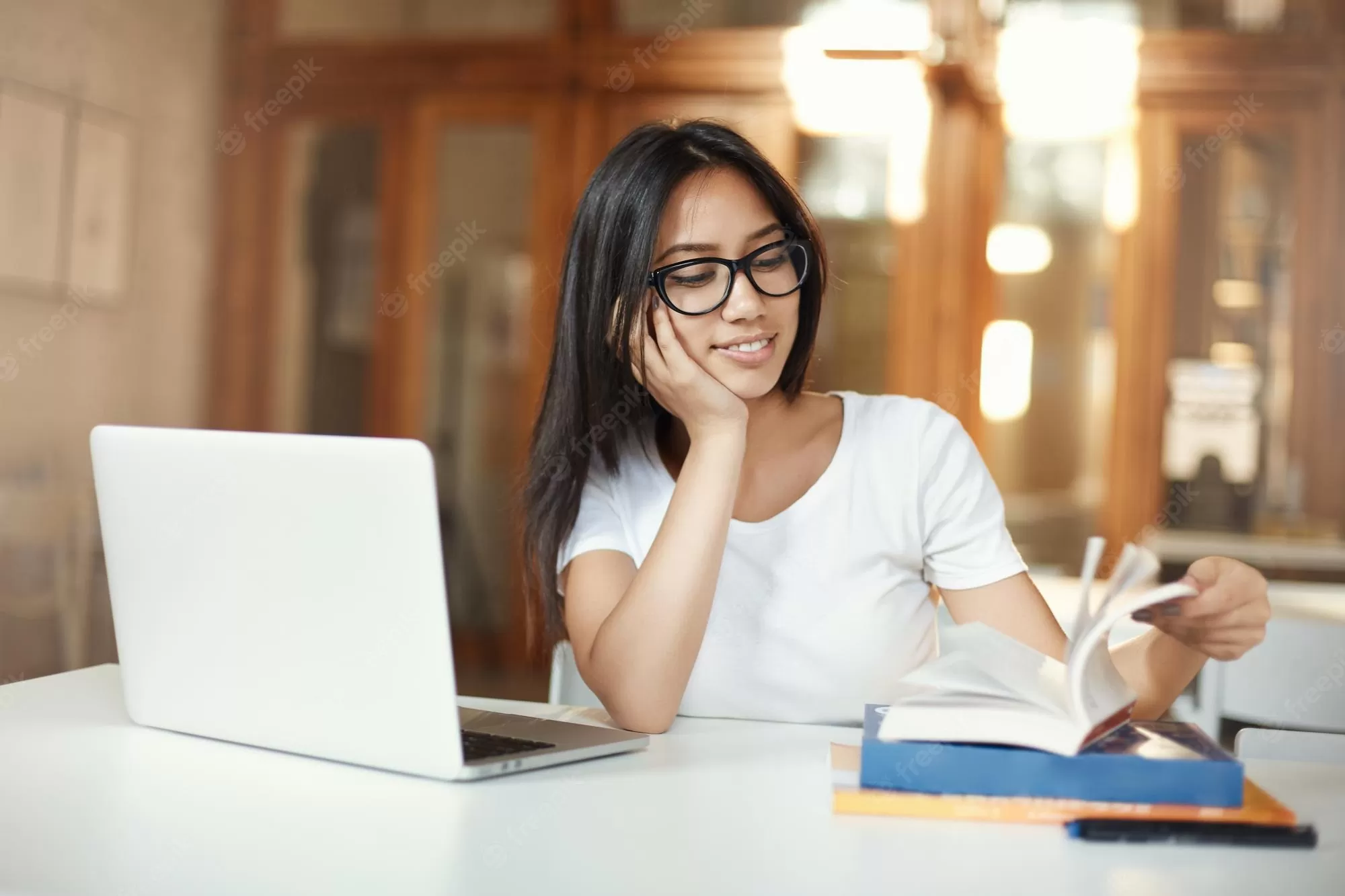 smiling female student skimming through study book while working her bachelor diploma open space library 197531 30684